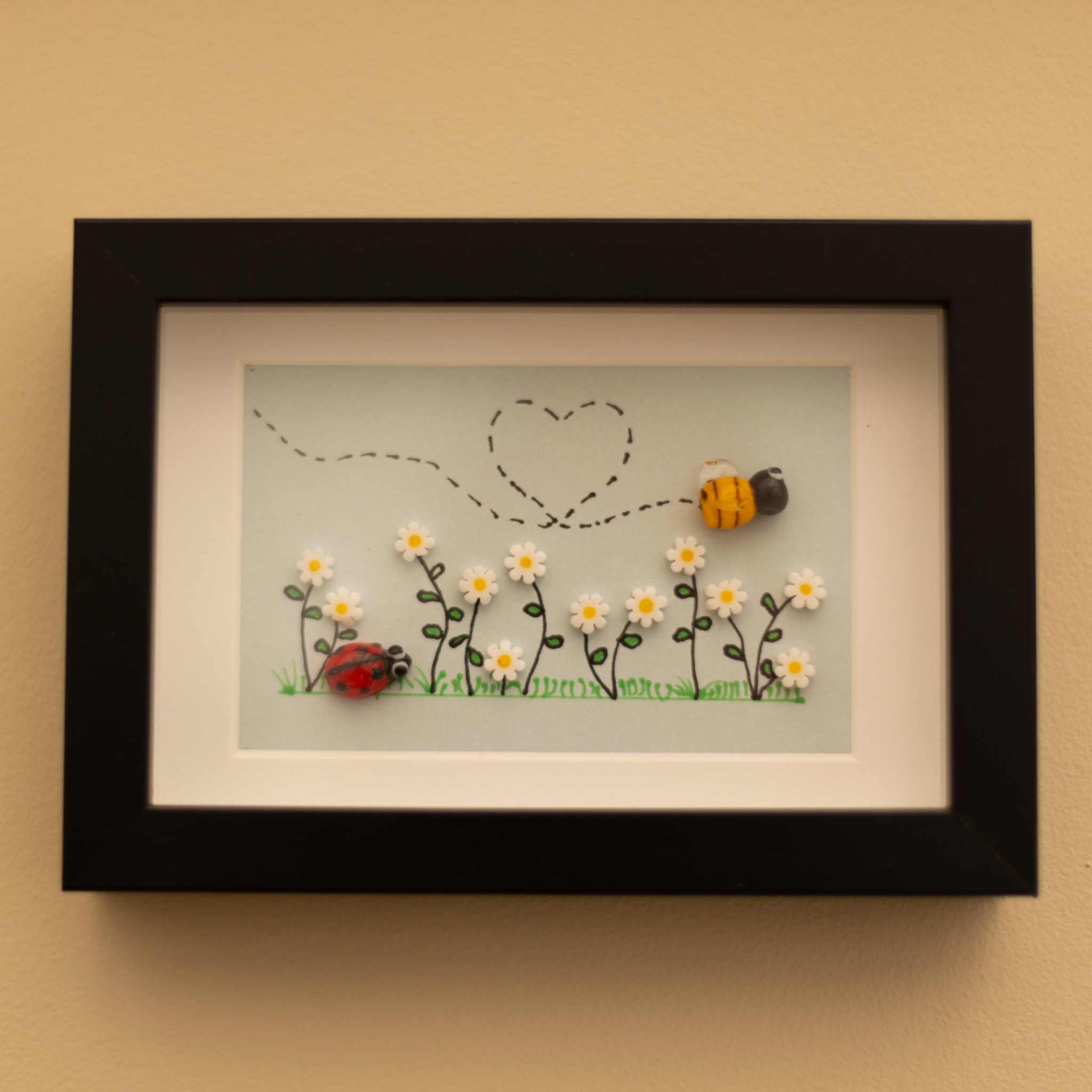 Framed bee and daisy artwork with black frame.