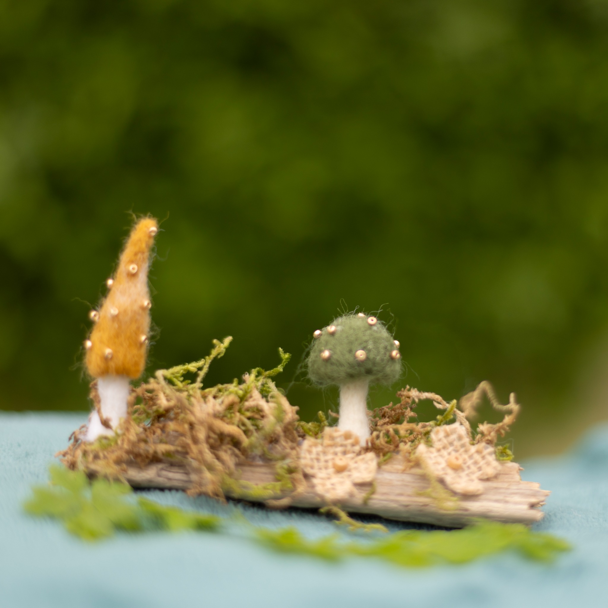 Miniature needle-felted woodland scene with mushrooms and moss.