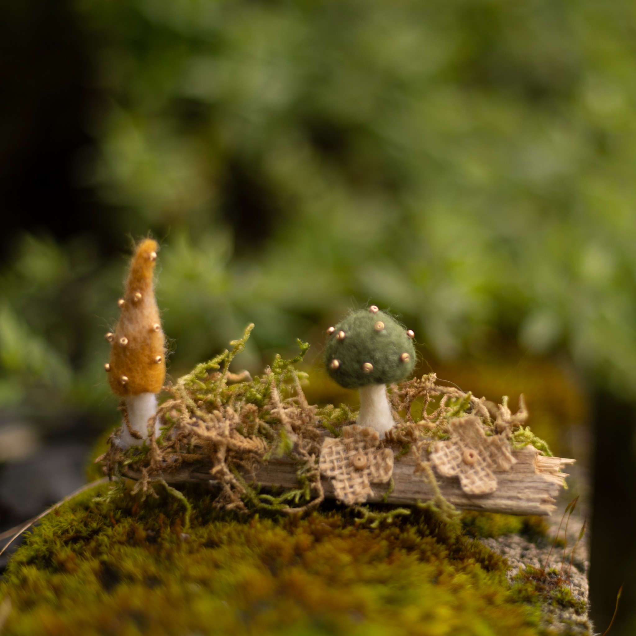 Needle-felted woodland scene displayed outdoors on moss.